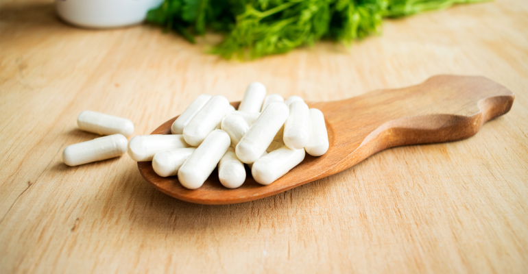 A small pile of Vitamin K pills in a wooden serving spoon.